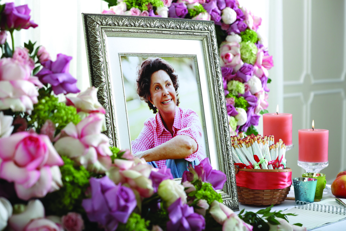 A framed portrait sits among candles, flowers and customized take-away pencils. 