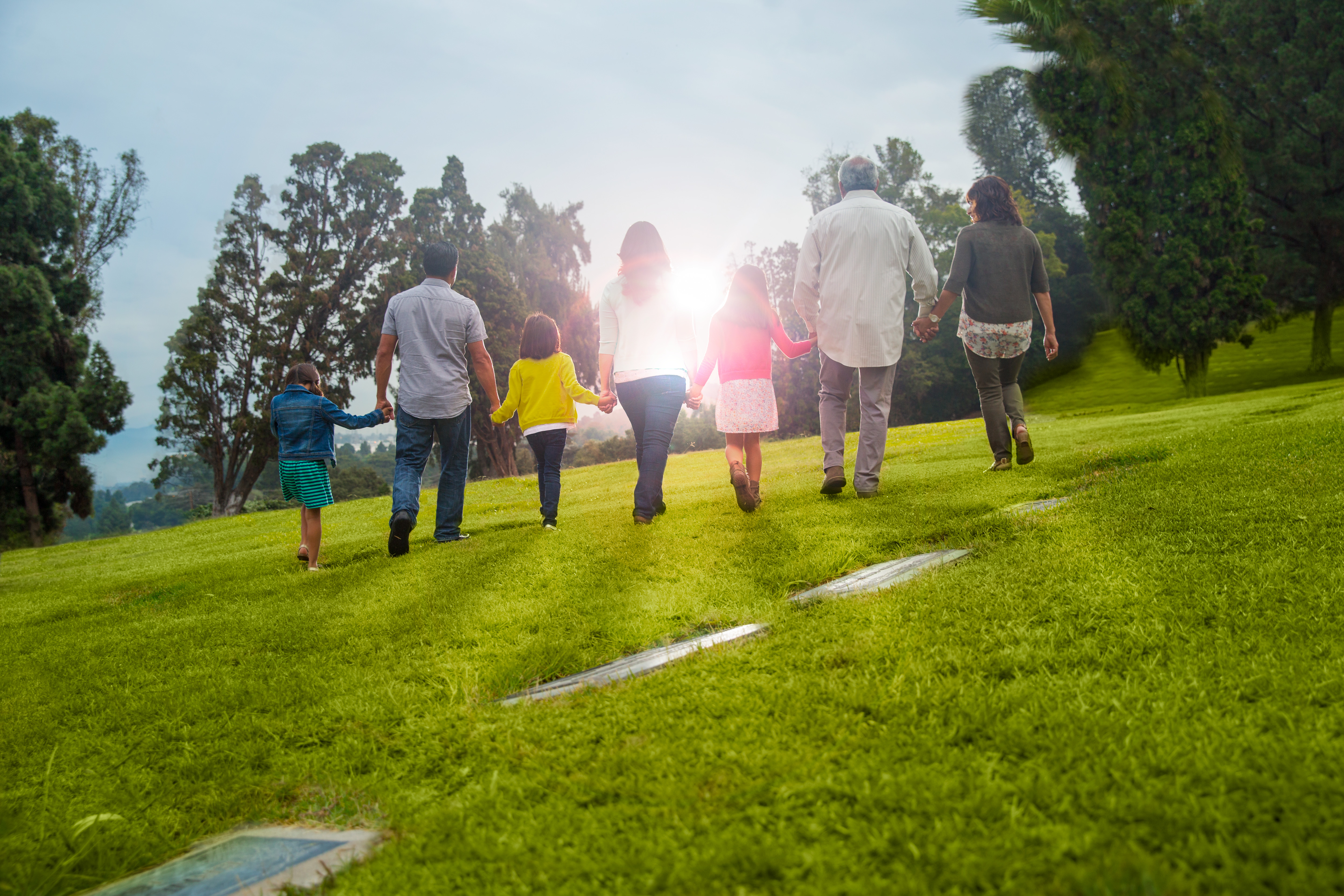 Three generations of a family walk toward the sun on a visit to their place of remembrance.  