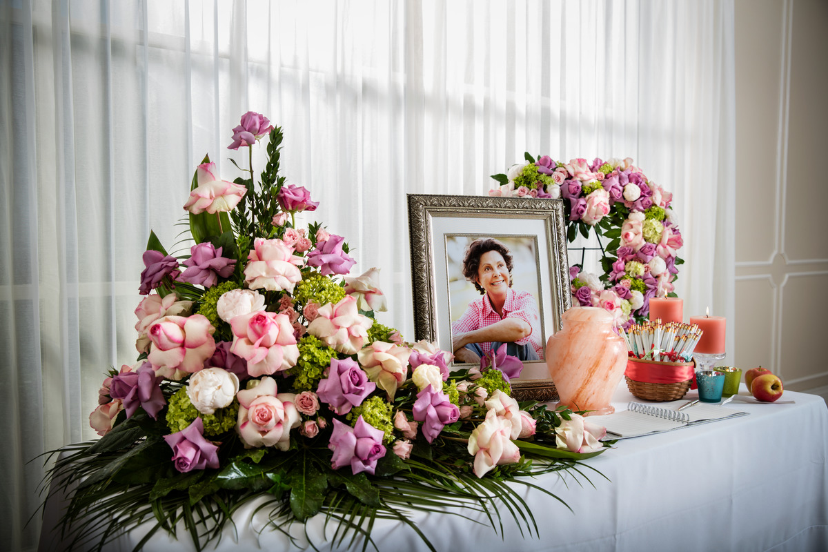 Memorial table with framed photo of older woman and beautiful floral arrangement. 