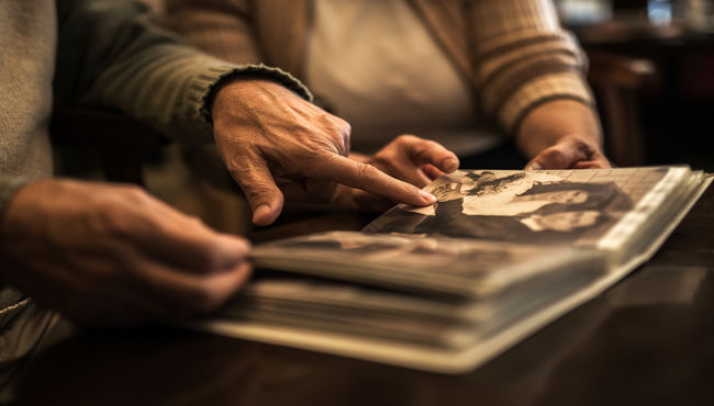 Pareja de ancianos señalando una foto de boda en un álbum de fotos.