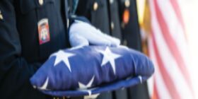 White gloved hands hold a folded American flag.
