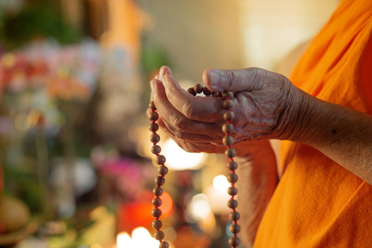 Buddhist monk's hands holding prayer beads