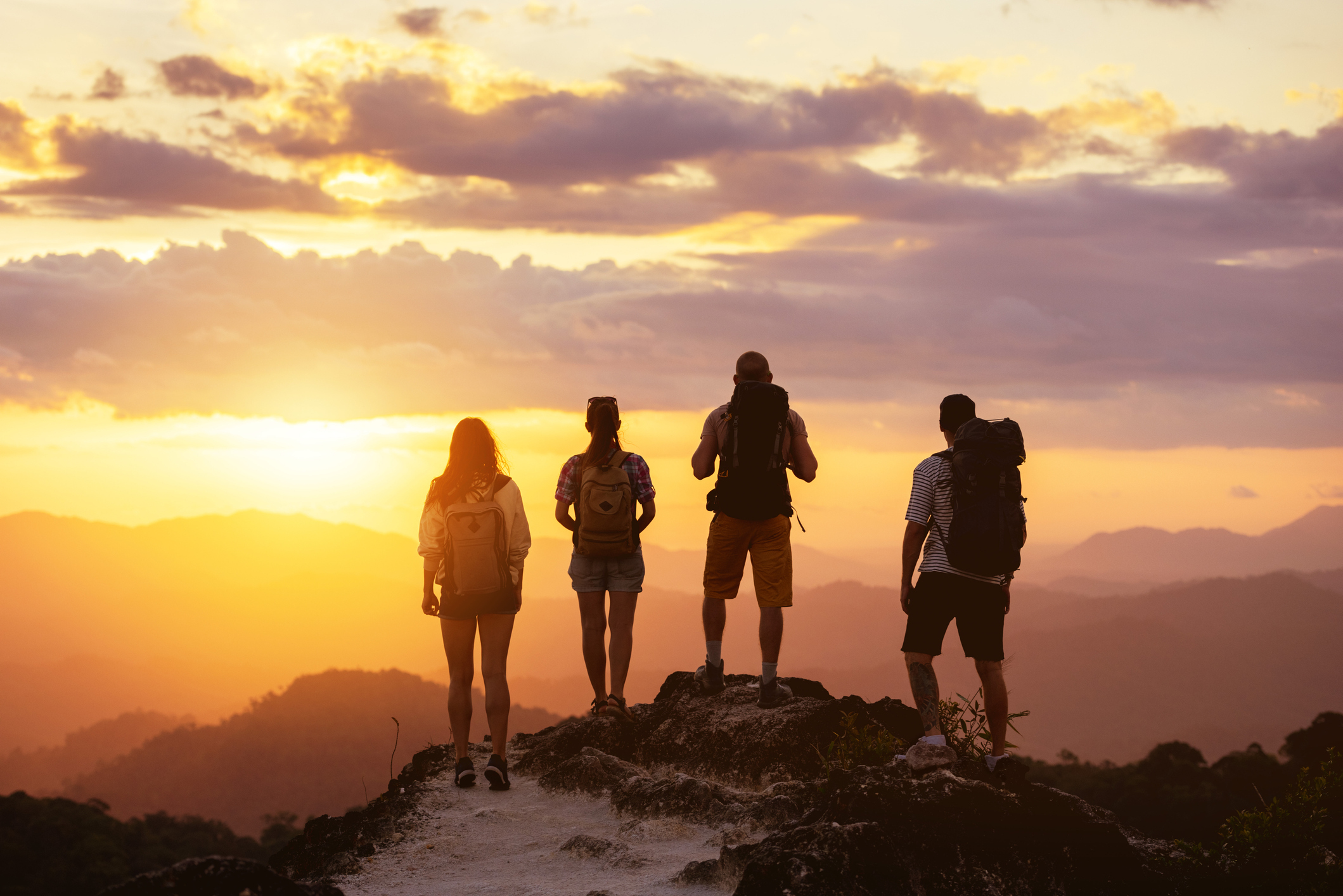 four people looking out at sunset on a mountain top